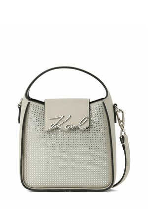 Petit sac à main beige avec des clous argentés, une poignée courte, une bandoulière amovible et un logo argenté "Karl" sur le rabat avant.
