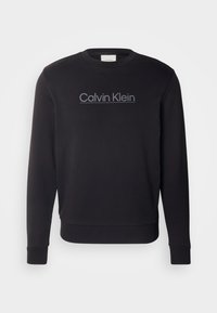 Felpa nera realizzata in materiale morbido, con collo tondo e maniche lunghe. Logo "Calvin Klein" grigio sul petto.