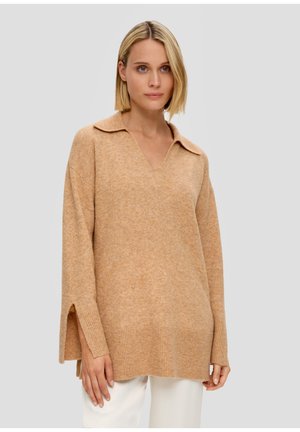 Pull en tricot beige avec un col en V et un large col. Présente des fentes latérales à l'ourlet et des poignets côtelés. Texture douce et coupe décontractée.