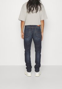 Mörkblå jeans med slim fit, med en distinkt design på bakfickan, subtila sömdetaljer och en läderetikett på midjan.