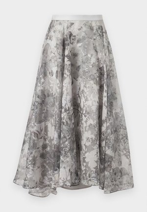 Woman wearing a sleeveless gray floral dress with layered ruffled neckline and an asymmetrical hem, standing against a white background.