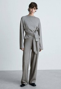 Graues Strick-Zweiteiler-Outfit mit einem Langarmtop, das an der Taille einen gebundenen Akzent hat, und weit geschnittenen Hosen, beide aus einem weichen Material.