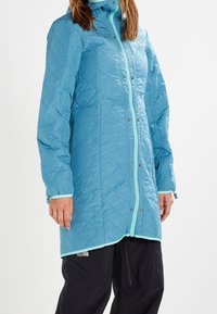 Hellblaue gesteppte Jacke mit Kapuze, ausgestattet mit einem Reißverschluss vorne und kontrastierenden helleren blauen Akzenten. Lange Ärmel und ein knielanger Schnitt.