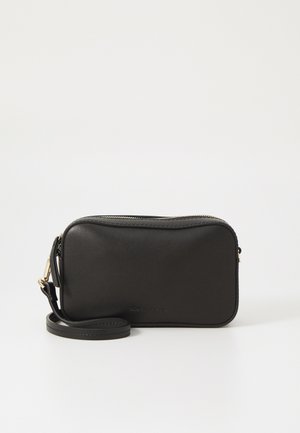Black leather crossbody bag with a zip closure, rounded rectangular shape, detachable strap, and subtle branding embossed on the front.