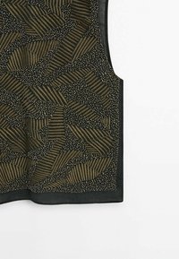 Haut noir sans manches avec des motifs abstraits de feuilles marron et de petits points blancs, doté d'un col rond et d'un ourlet droit.