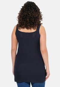Top senza maniche blu navy con un tessuto rilievo e scollo quadrato. Presenta spalline larghe e una vestibilità morbida e lunga.
