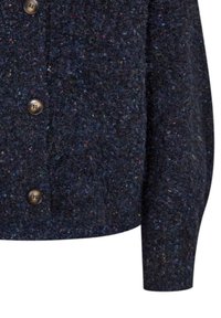 Donkerblauwe, textuurgebreide cardigan met meerkleurige stippen, voorzien van ronde donkere knopen aan de voorkant en lange mouwen.