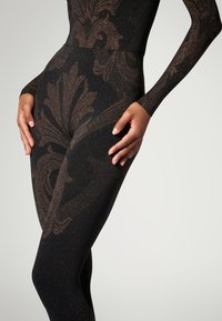 Sorte leggings med et glitrende guld- og brunt udsmykket mønster, med en glat tekstur og tætsiddende design.