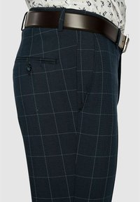 Granatowe spodnie w kratę z teksturowanej tkaniny, z jedną tylną kieszenią, szerokimi szlufkami na pasek oraz zapięciem na guzik.