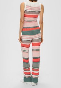 Ensemble en tricot composé d'un haut sans manches et d'un pantalon évasé. Motif rayé dans des nuances de rose, corail, vert et gris. Tissu texturé.