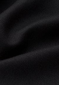 Black fabric with fine ribbed texture and soft folds creating gentle shadows and highlights.