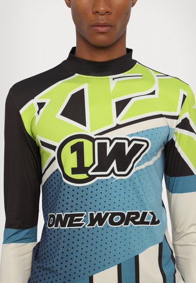 Long-sleeve top featuring a geometric design in black, green, and blue, with text "1W" and "ONE WORLD" and dotted patterns across the fabric.