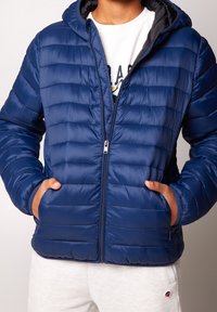 Navy puffer jacket with a quilted design, hood, and zipper front. Features two side pockets and sleek, smooth texture.