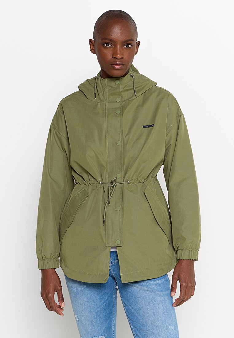 Oliwkowa kurtka z kapturem, z regulowanym pasem i zapięciem na napy. Posiada elastyczne mankiety oraz kieszenie boczne. Wykonana z gładkiego, lekkiego materiału.