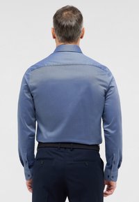 Blauw overhemd met lange mouwen en een textuurpatroon, met een contrasterende kraag en manchetten. Geknoopte mouwen en een getailleerde pasvorm zijn zichtbaar.