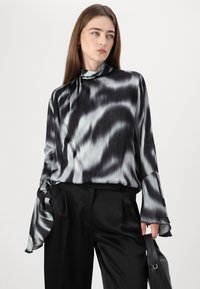 Svart og sølv satengbluse med høy hals, lange ermer og draperte mansjetter, med et bølgedesign og en glatt tekstur.