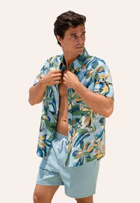 Koszula krótki rękaw z wielokolorowym wzorem kwiatowym; lekki materiał; zestawiona z jasnoniebieskimi szortami kąpielowymi z regulowanym sznurkiem.