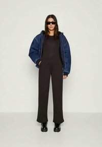 Σκούρα κοντή φόρμα σε συνδυασμό με τζάκετ από μπλε τζιν, μαύρα γυαλιά ηλίου και χοντρές μαύρες μπότες. Λείες υφές με αντιθετικά χρώματα.