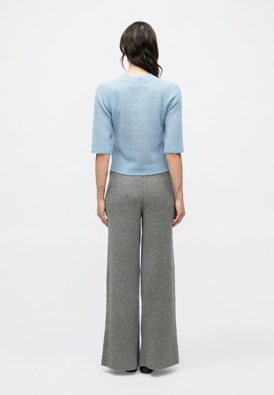 Pulover tricotat de culoare albastru deschis, cu mâneci scurte, asortat cu pantaloni gri evazați cu textură nervurată. Textură netedă și design mulat.