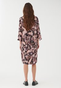 Svart blommig klänning med paisley- och botaniska mönster. Har trekvartslånga ärmar och en lös passform, tillverkad av lättviktig tyg.