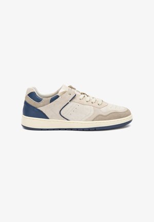 Baskets en suède beige clair avec des accents en cuir bleu marine, bout arrondi et fermeture à lacets. Comprend des détails perforés et une semelle en caoutchouc.