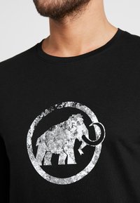 Czarna bawełniana koszulka z krótkim rękawem z grafiką zniszczonego białego mamuta umieszczoną w okrągłej ramce, z okrągłym dekoltem.