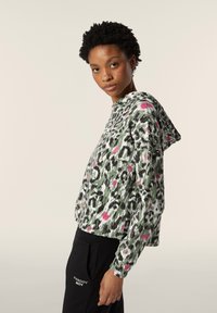 Felpa cropped con cappuccio in stampa leopardata verde, nera e bianca con dettagli rosa; presenta una vestibilità comoda e cappuccio con lacci.