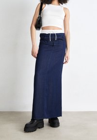 Džínová maxi sukně v tmavě modré barvě se volným střihem, vybavená elastickým pasem a šňůrkou, doplněná o robustní černé platformové boty.