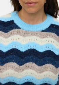 Gebreide trui met een lichtblauw, marineblauw, beige en crèmekleurig golfpatroon. Zachte textuur met een lichtblauwe geribde kraag.