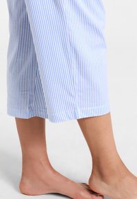 Vaaleansinisiä ja valkoisia raidoitettuja lahkeita, jotka on valmistettu pehmeästä kankaasta. Housuissa on suora lahjemuoto ja viimeistelytikkaukset.