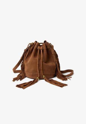Bruine suède bucketbag met trekkoordsluiting, lange schouderriem en decoratieve franje kwastjes op een witte achtergrond.