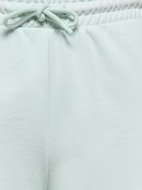 Jasnoniebieskie spodnie z elastycznym pasem i wiązanym sznurkiem oraz miękką, gładką fakturą materiału.