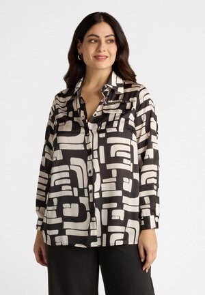 Langärmlige Bluse mit Knopfleiste in Schwarz und Weiß, ausgestattet mit abstrakten geometrischen Mustern, seidigem Textur und einer Brusttasche, die mit Reißverschlüssen akzentuiert ist.