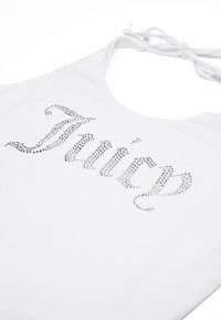 Canotta bianca con un lucido logo in strass "Juicy". Il tessuto è liscio e presenta un design a collo halter con sottili spalline da annodare.
