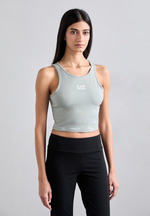 Lys grøn cropped tanktop med rund udskæring og logoet "EA7" i hvid. Sammen med høj talje sorte træningsbukser.