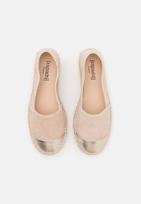 Scarpe slip-on in suede beige con punta metallica dorata, bordi cuciti e interno liscio. Suola espadrille piatta e flessibile.
