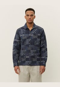 Navy button-up shirt with varied geometric and floral patterns. Long sleeves, collared design, and textured fabric. Classic fit.