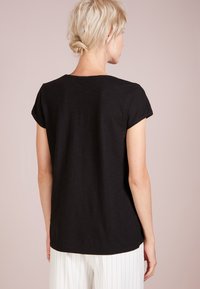 Schwarzes T-Shirt mit kurzen Ärmeln und lässiger Passform, aus weichem Stoff. Rundhalsdesign und glatte Textur, Ansicht von hinten.