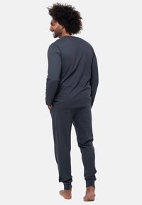 Maglietta a maniche lunghe grigia scura e pantaloni jogger abbinati, realizzati in morbido tessuto con una vestibilità rilassata. I pantaloni hanno polsini elastici e tasche laterali.