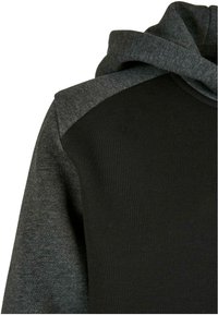 Felpa con cappuccio dal corpo nero e pannelli spalle texture grigio scuro. Tessuto morbido con cappuccio funzionale, che mostra un design sportivo.