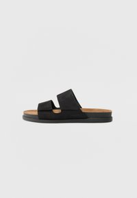 Black leather slide sandals with two wide straps, a cork footbed, and a textured rubber sole. Minimalistic design with no embellishments.