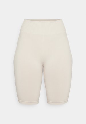 Shorts de vélo beige moulants avec une taille côtelée, fabriqués en tissu lisse, présentant un design sans couture et une coupe au niveau des genoux.