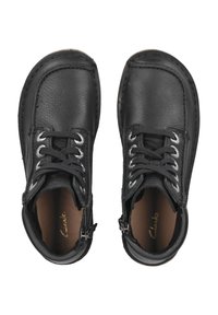 Botas de tobillo de cuero negro con punteras redondas, que presentan detalles en plata, acabado texturizado y cordones tradicionales. Construcción duradera y tacón bajo.