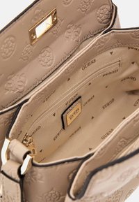 Borsa a mano in pelle beige con motivo del logo in rilievo, hardware dorato, tasca con zip e interno foderato con nome del marchio stampato.