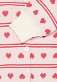 Cardigan rose avec poignets blancs et fermeture à boutons, orné de motifs de cœurs rouges et de rayures horizontales sur le tissu.