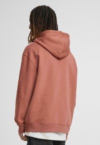 Hættetrøje i blød, støvet rosenfarvet stof; har ribstrikkede manchetter og kant; afslappet pasform med en rummelig ryg; minimalistisk design.