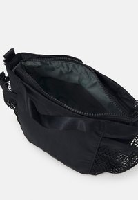 Borsa nera con un pannello laterale in rete, chiusura a zip e rivestimento interno grigio scuro. Presenta un corpo strutturato e spallacci rinforzati.
