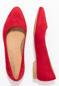 Ballerines en daim rouge avec un bout pointu et un petit talon transparent. L'intérieur est doté d'une doublure beige avec un logo imprimé.