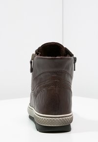 Braune Leder-Ankle-Boots mit strukturiertem Finish, seitlichem Reißverschluss, weißer Gummisohle und dekorativen Nähten.