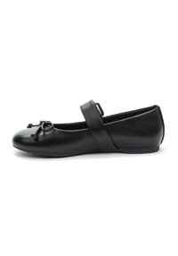 Scarpa piatta nera in pelle con punta arrotondata, dettaglio decorativo a fiocco e cinturino regolabile sulla parte superiore del piede. Texture liscia, design minimalista.